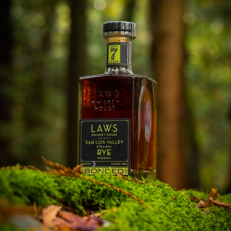 laws whiskey house bottle sitting on green moss with foliage in the background