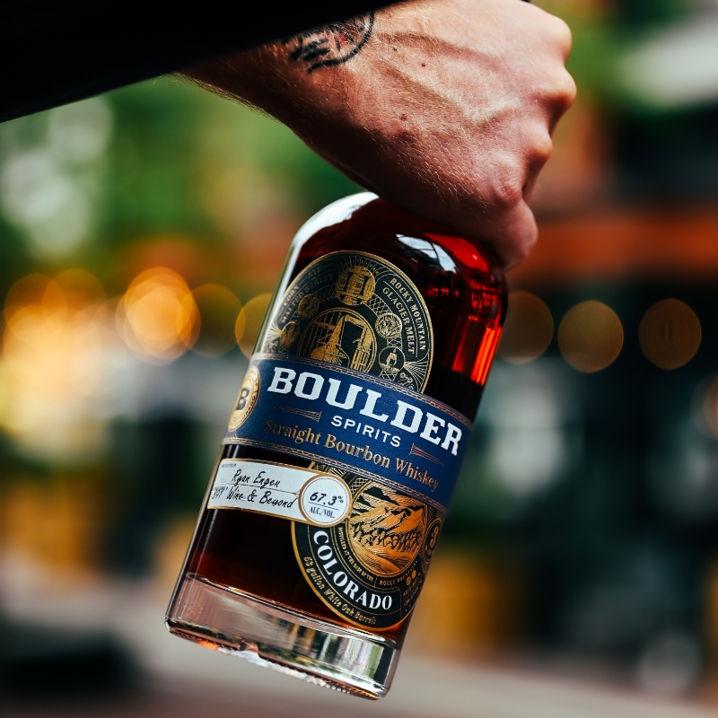 Boulder Straight Bourbon Whiskey being held against a bokeh background